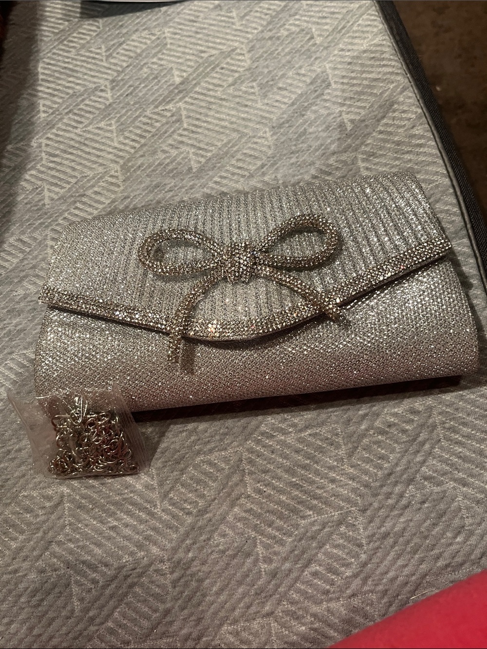 Silver glitter clutch with rhinestone bow accent and optional chain strap